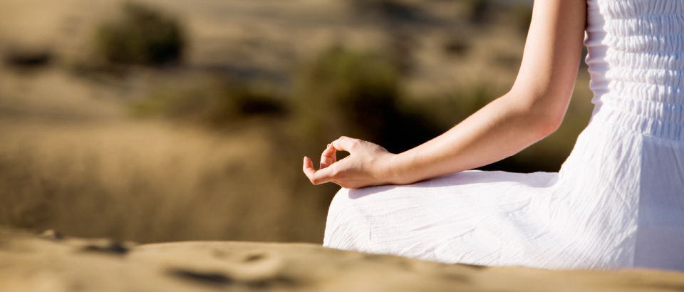 Frau in weißer Kleidung, die Hand in Meditationshaltung